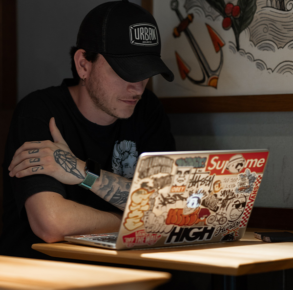 A man wearing a cap working at a computer, managing product images and files for a B2B webshop.
